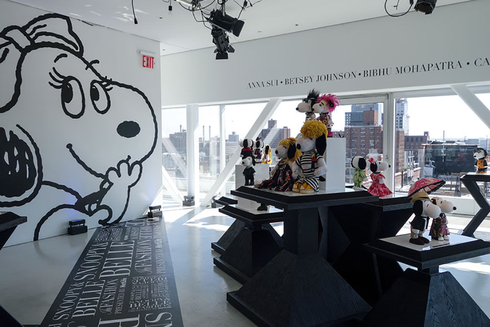A bright, indoor space with large windows, several tables displaying small black and white dog statues and a large illustration of a dog on the wall.