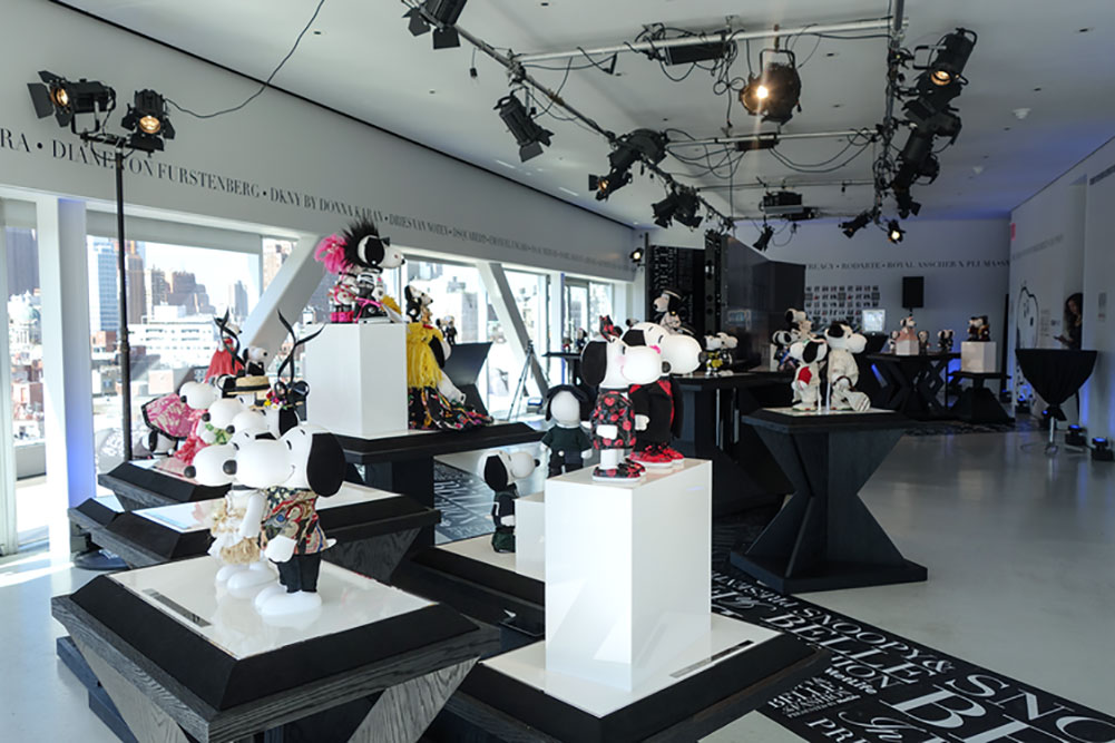 An indoor space with black and white decor and several tables displaying statues of black and white dogs wearing designer costumes.