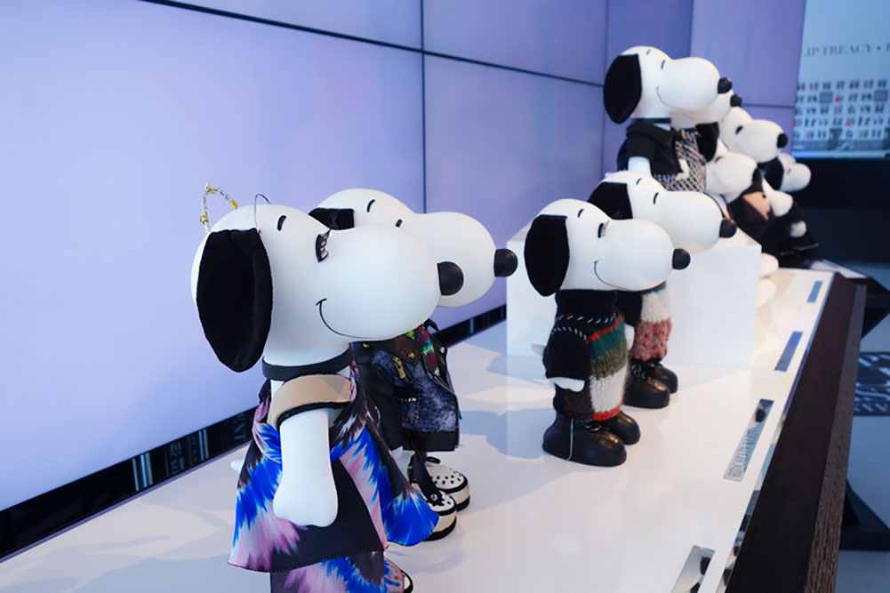 A close-up of small black and white dog statues on display, wearing designer costumes.