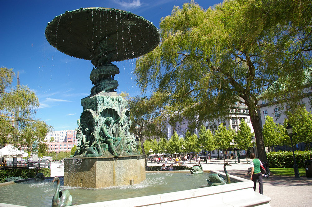 A tall, round water fountain in the middle of a city park.