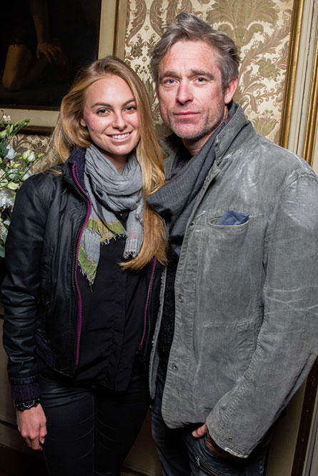 A blonde woman and a grey haired man posing for a photo at an event.
