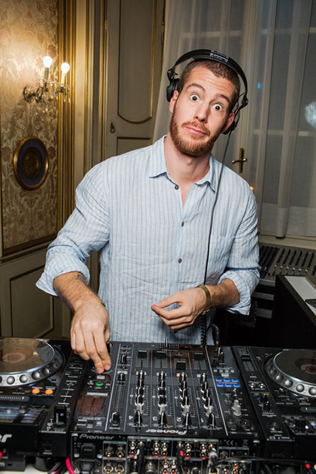 A male DJ, wearing a light blue shirt, making a funny face.