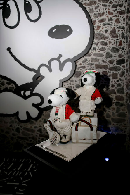 A dark indoor space with a display of two black and white dogs wearing red and white outfits.