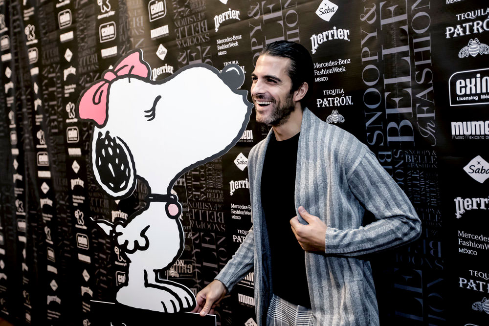 A man laughing and  standing in front of a black and white branded wall.