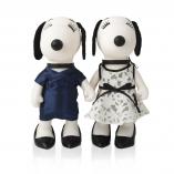 Two black and white dog statues in front of a white background. The dog on the left is wearing a dark blue dress and the one of the right side  is wearing a black and white dress.