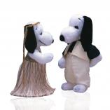 Two black and white dogs In front of a white background facing each other. The dog on the left is wearing a long, gold skirt and a hold headpiece. The dog on the right is wearing beige pants and a beige vest.