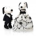 Two black and white dog statues in front of a white background. The dog on the left s wearing a black suit and the dog on the right is wearing a black and white ball gown.