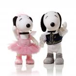 Two black and white dog statues in front of a white background. The dog on the left is wearing a pink ballerina dress and the dog on the right side is wearing white pants and a black vest.