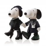 Two black and white dog statues holding hands in front of a white background. They are dresses in black.
