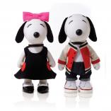 Two black and white dog statues in front of a white background. The dog on the left is wearing a black dress and a pink bow on her head. The dog on the right is wearing a red and white jacket with black pants.