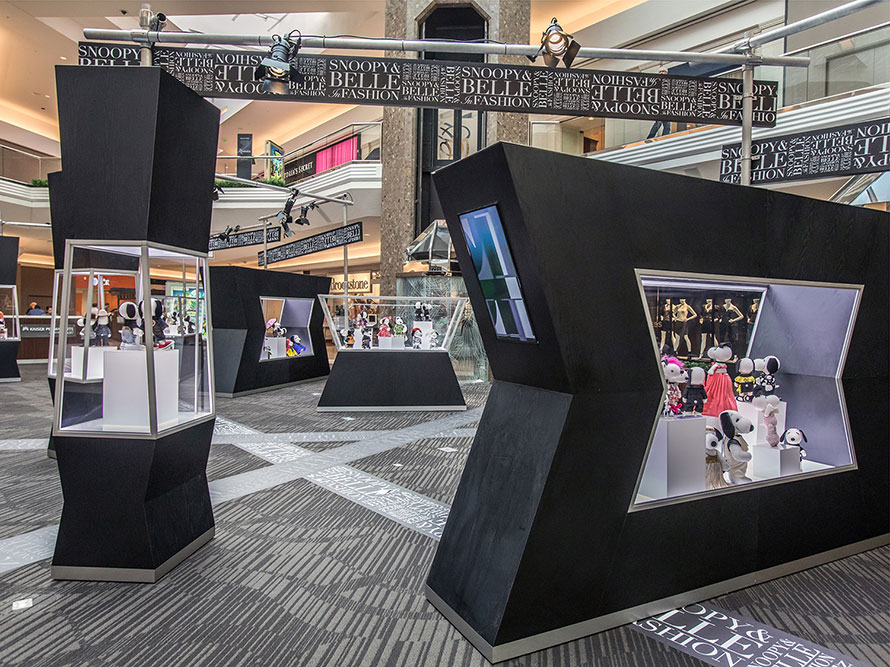An indoor space with several black and glass displays featuring black and white dog statues.