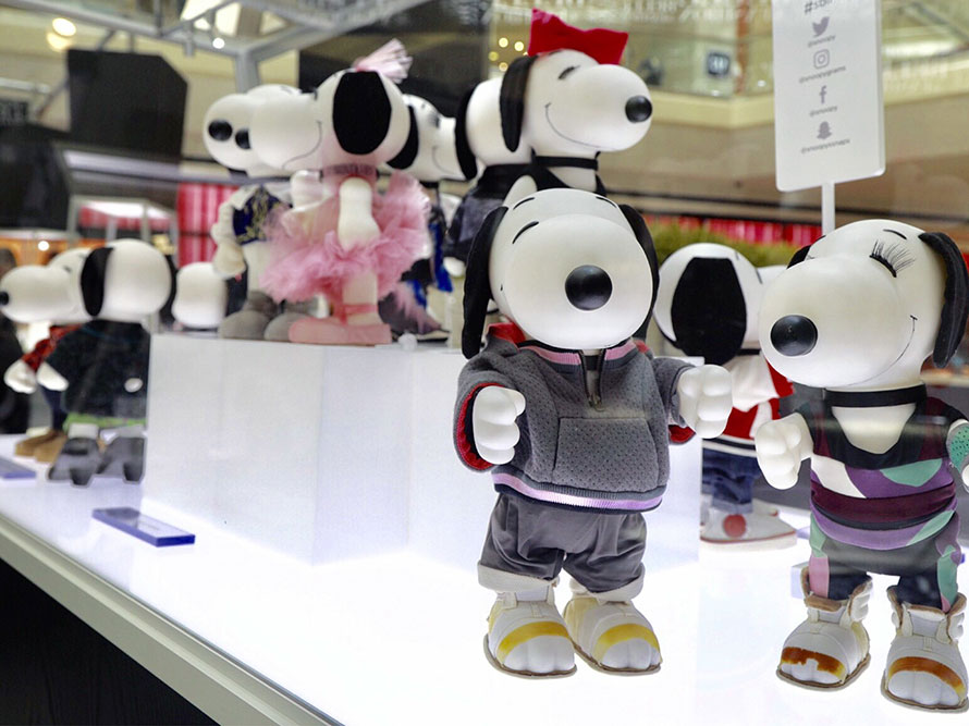 A close-up view inside a glass display of black and white dog statues wearing various outfits.