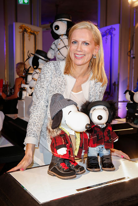 A women with short blonde hair smiling and leaning over towards a display of two black and white dog statues.