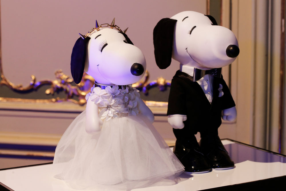 A close-up of two black and white dog statues on display. One is wearing a white gown and the other one a black suit.