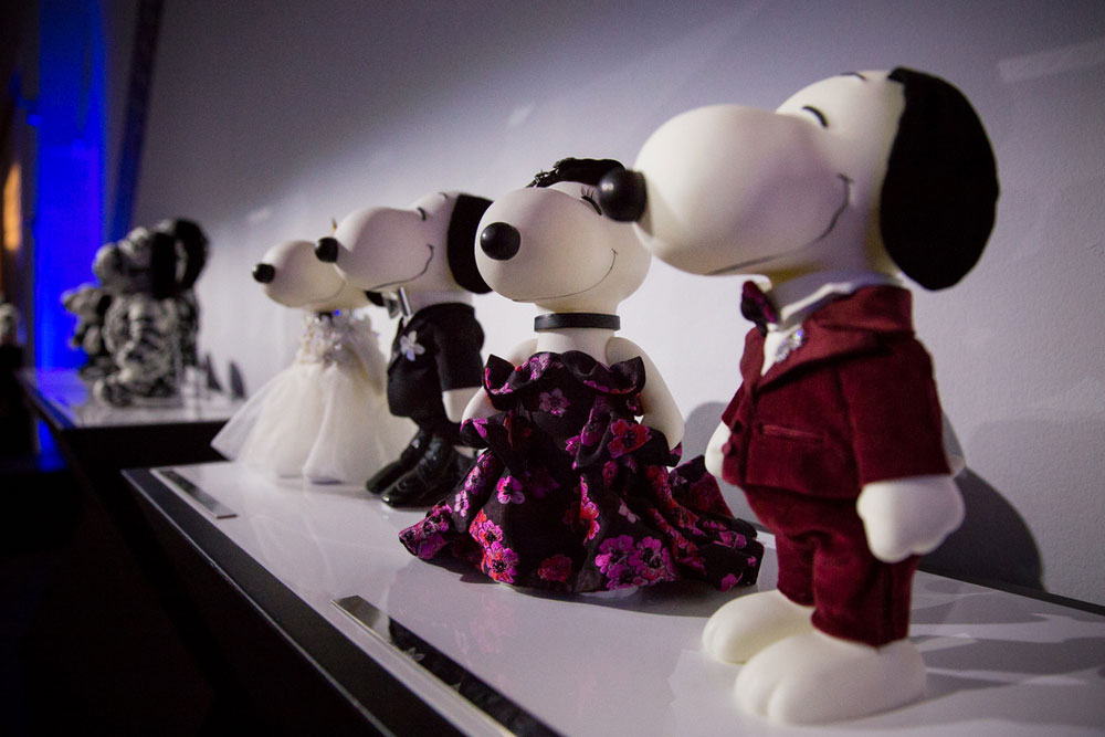 Four black and white dog statues on display in an darkly lit room.
