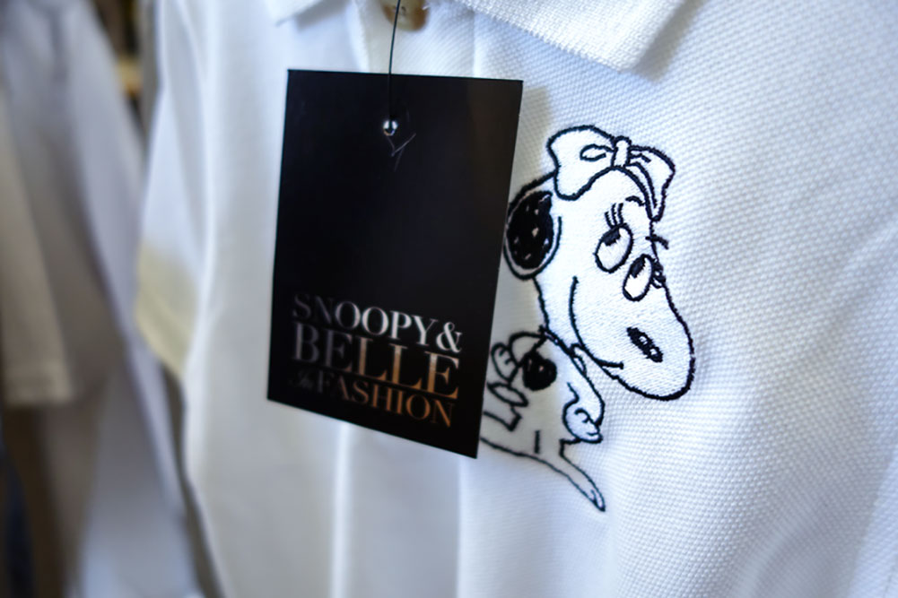 A close up of a black price tag hanging off a white shirt with a small illustration of a dog.