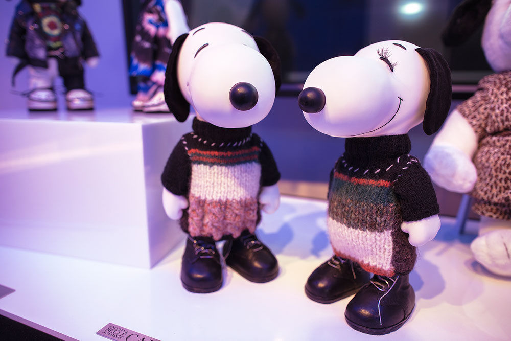 A close-up of two black and white dog statues on display, wearing wool sweaters. 
