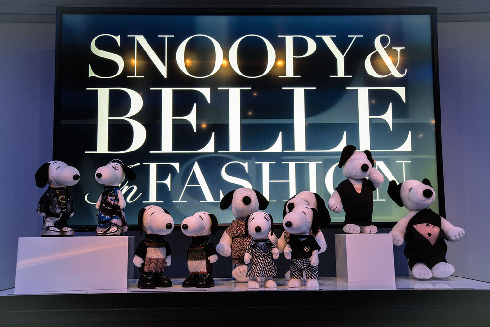 A display of black and white dog statues in front of a large TV screen that reads Snoopy and Belle in Fashion.