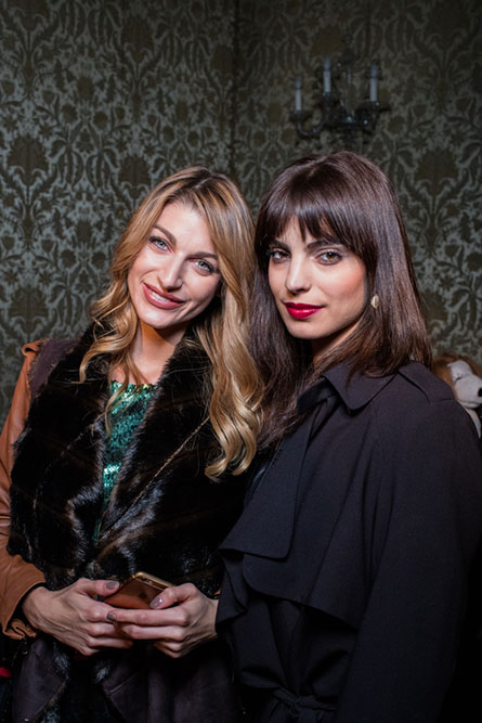 A blonde woman and a brunette woman posing for a photo at an event.