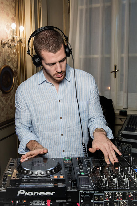 A DJ wearing a light blue dress shirt and headphones.