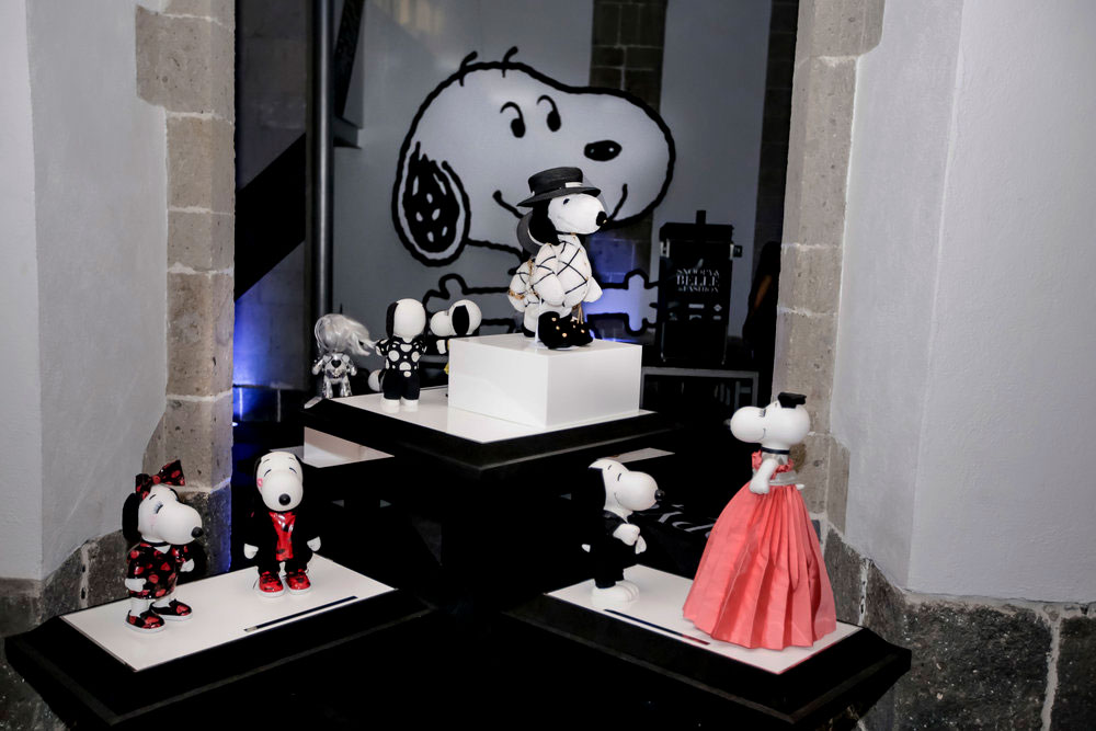 Black and white dog statues, wearing various costumes,  displayed on a black and white table.
