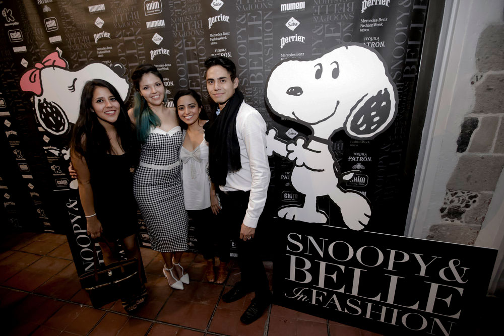 Four people posing in front of a black and white branded wall with a large illustration of a black and white dog.