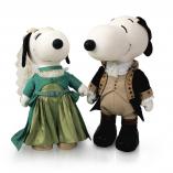 Two black and white dog statues in front of a white background. The dog on the left is wearing a green dress with a green jacket and a beige veil. The dog on the right is wearing a black and beige tuxedo.