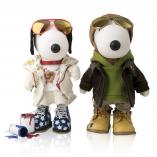 Two black and white dog statues in front of a white background. The dog on the left is wearing a beige outfit with blue shoes and gold aviators. The dog on the right has a green goodie, brown leather jacket and gold aviators.