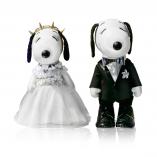 Two black and white dog statues in front of a white background. The dog on the left is wearing a white wedding dress and the dog on the right side is wearing a black suit.