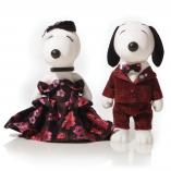 Two black and white dog statues in front of a white background. The dog on the left is wearing a red and black ball gown and the dog on the right is wearing a red suit.