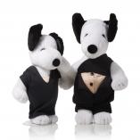 Two black and white dogs in front of a white background wearing black outfits.