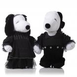 Two black and white dog statues in front of a white background wearing black, ruffly outfits.
