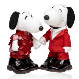 Two black and white dog statues in front of a white background. The dog on the left is wearing a red dress and the dog on the right is wearing a red suit.