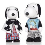 Two black and white dog statues in front of a white background. The dog on the left is wearing a red and blue dress with a black and white jacket. The dog on the right is wearing black and white pants with a blue shirt.